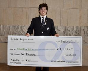 Lincoln presenting a cheque for $10,000.